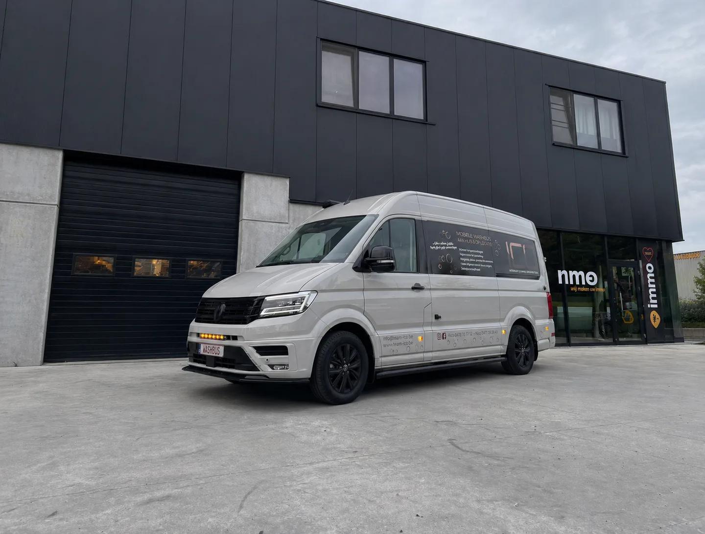ICO Washbus aan een modern beton gebouw bij zonsondergang